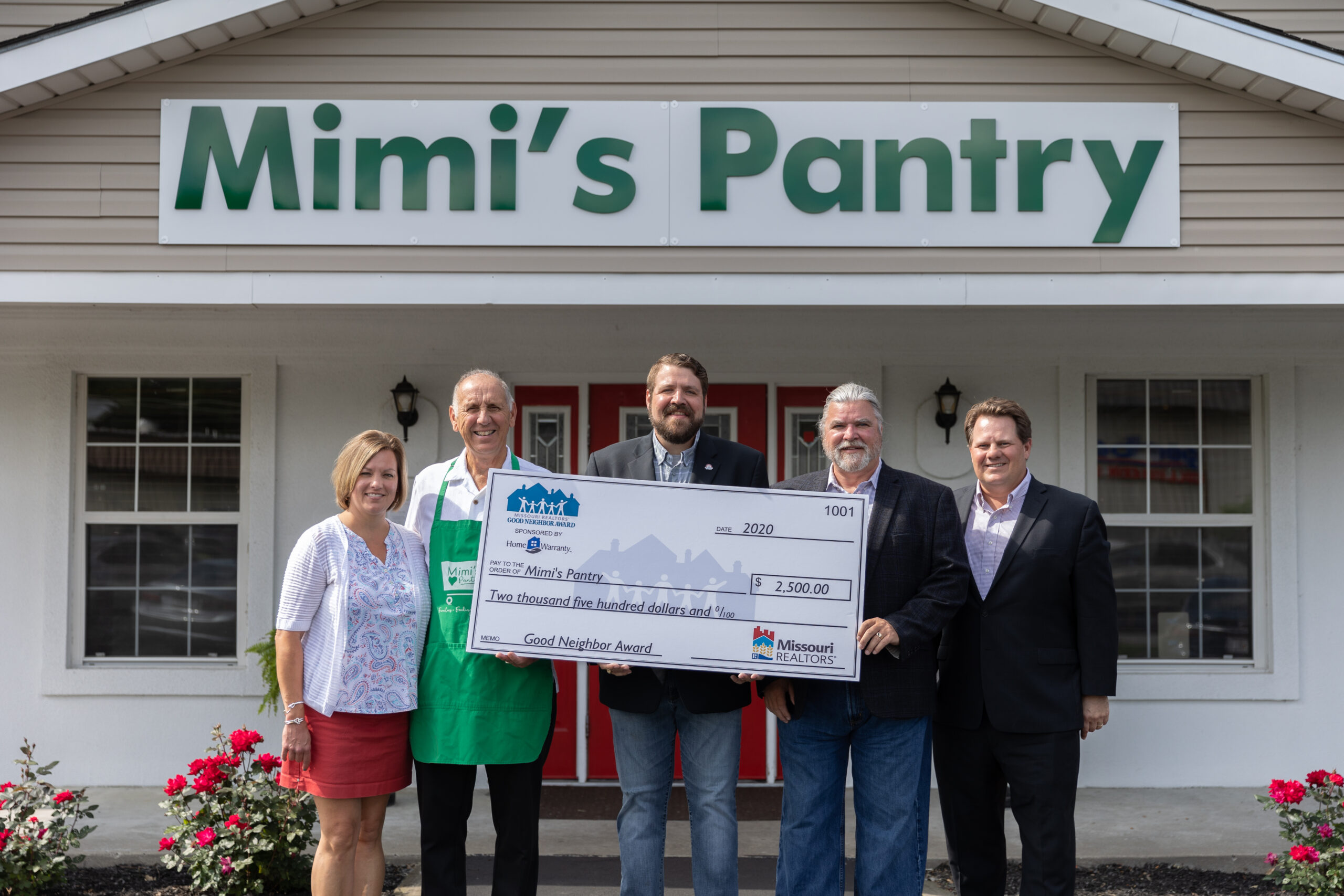 Image description: Dennis Curtin accepts his Good Neighbor Award check outside the Mimi's Pantry building.