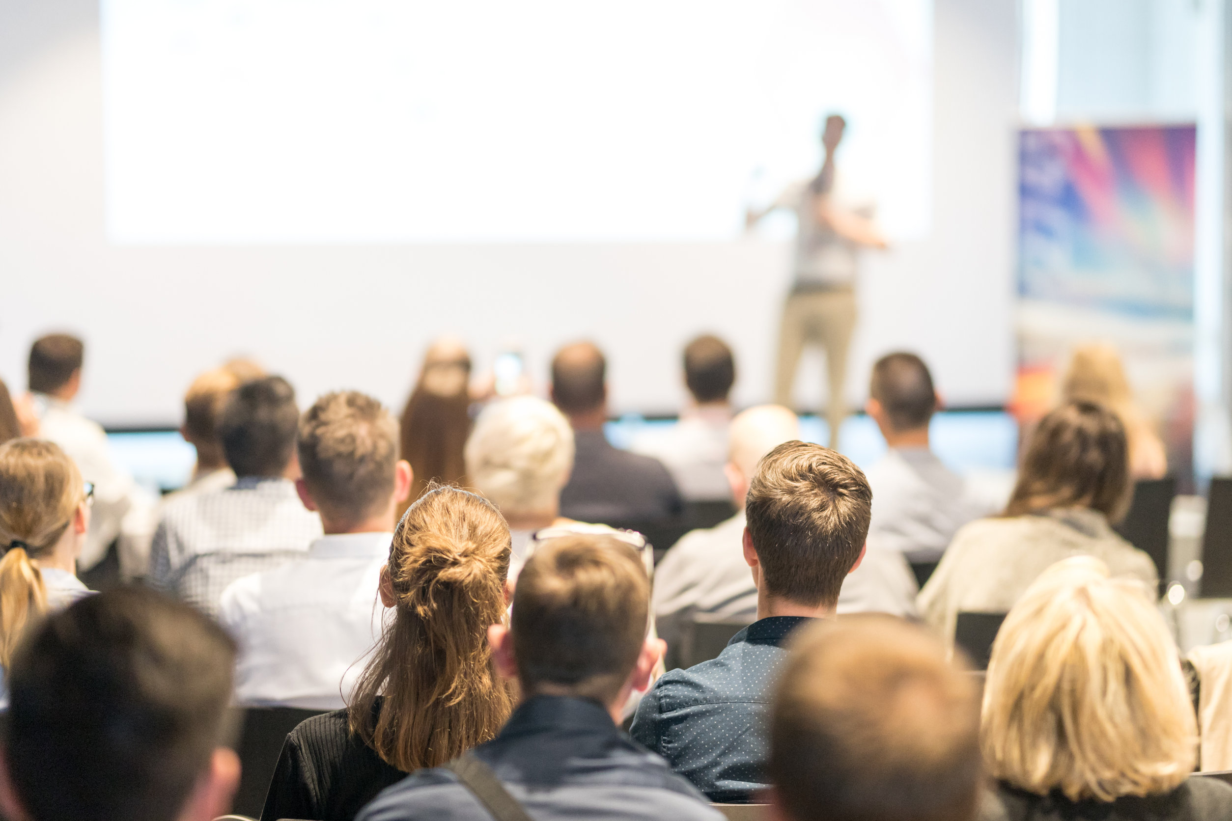 Image description: Rear view of unrecognized audience in classroom.