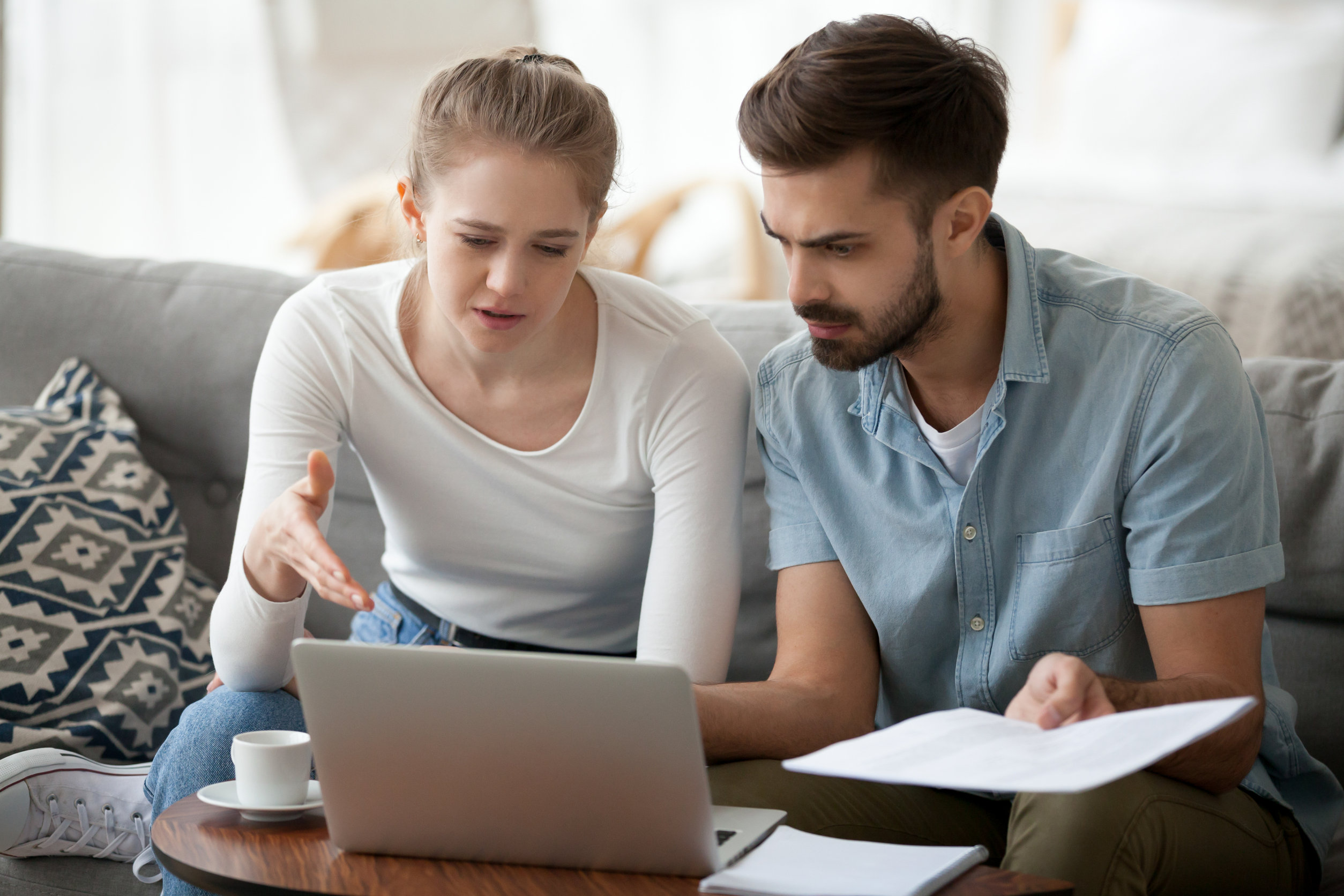 Image description: Two millennials discuss their finances in their home.