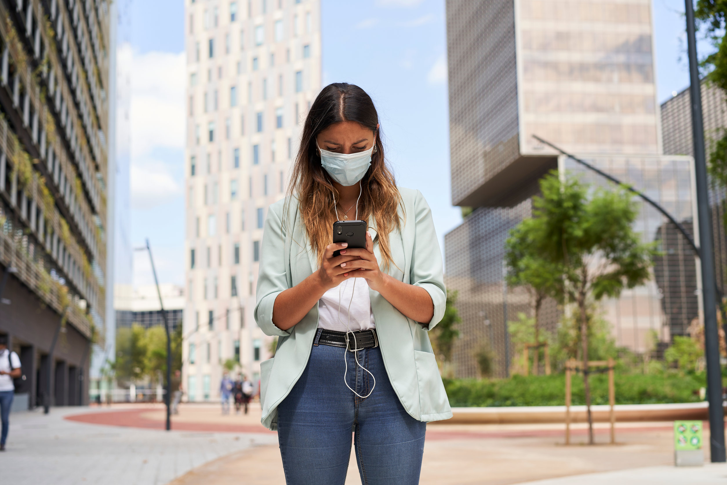 Image description: Young woman using the Noonlight safety app outdoors in the city.