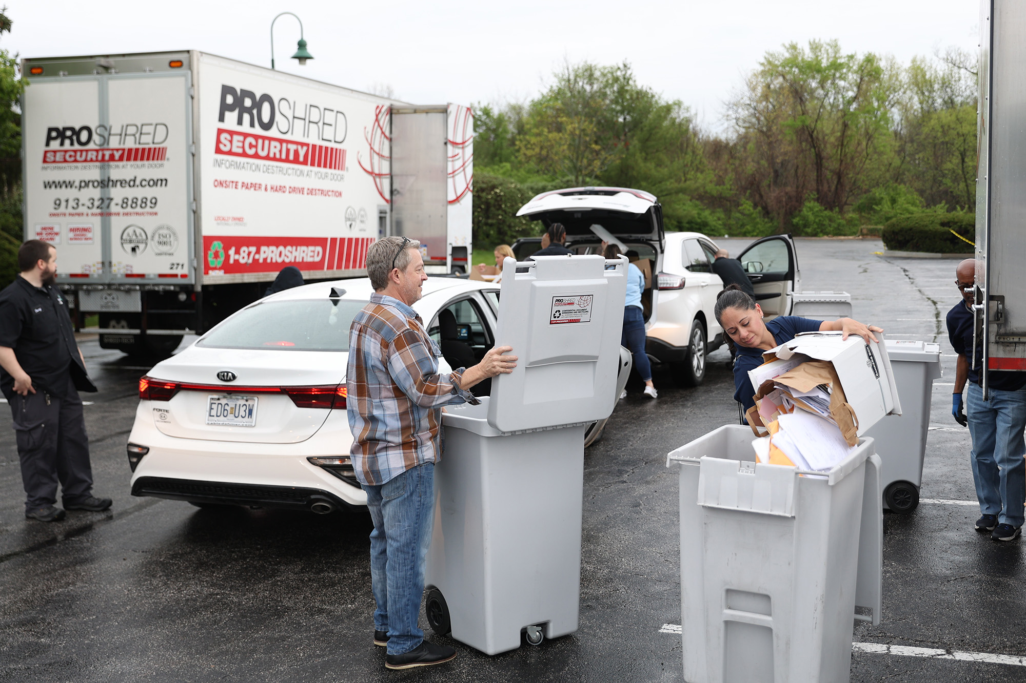 Image description: Volunteers and ProShred staff collecting shred materials from the line of cars at Shred Day 2022.