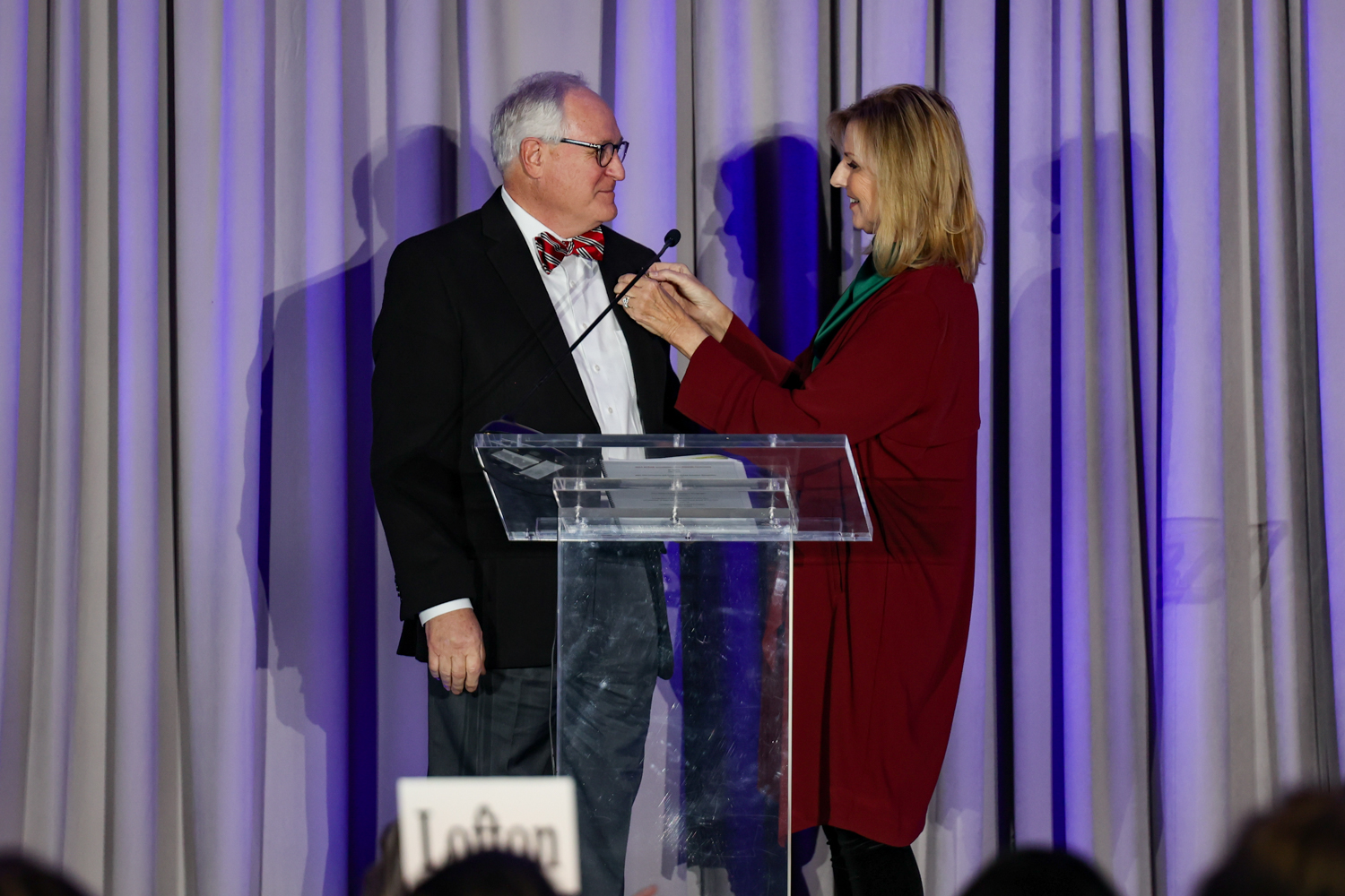 Image Description: 2021 REALTOR® of the Year Steve Moyer accepts his award and pin on stage with Chair of the Awards Committee.