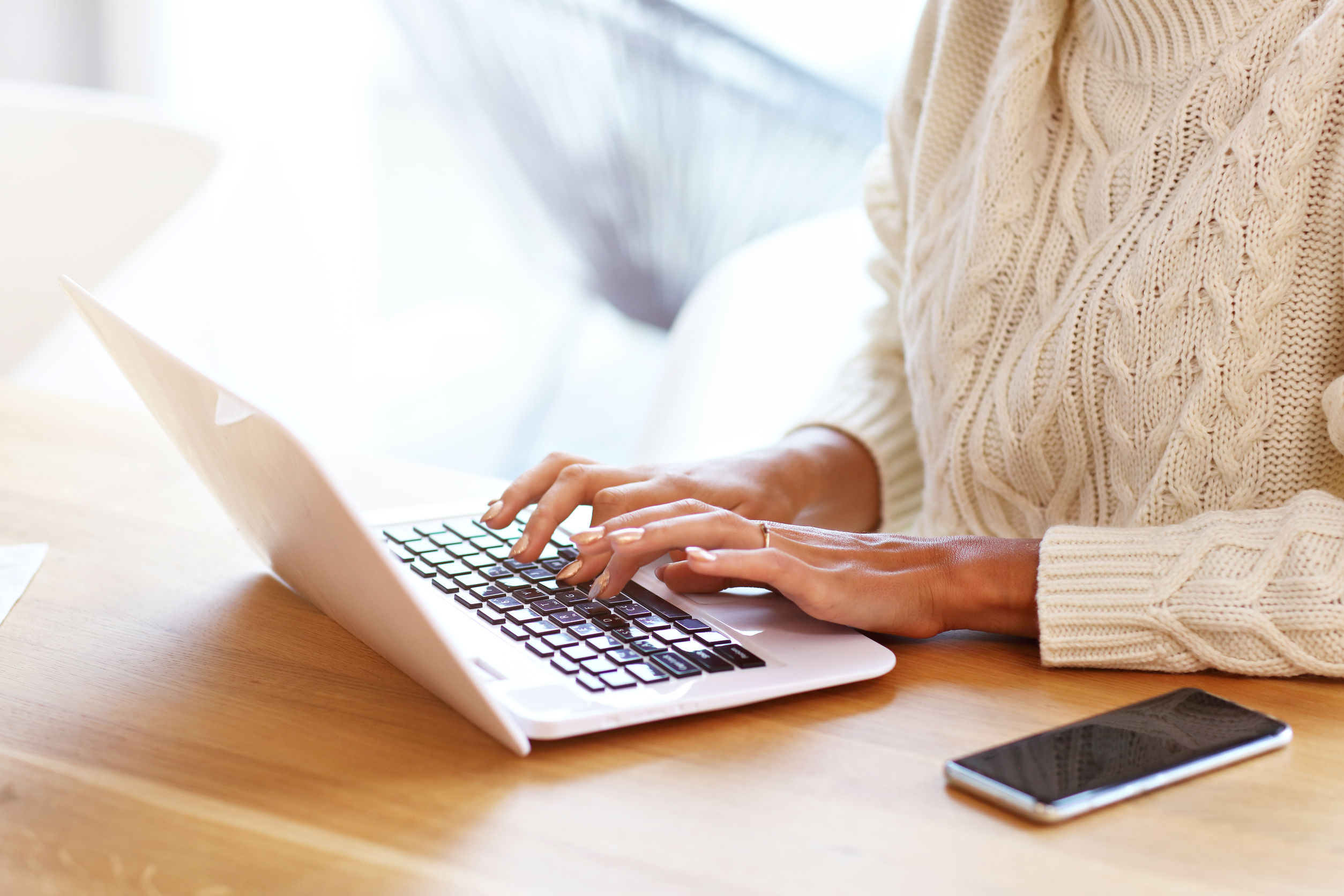 Image description: Picture of adult woman wearing warm sweater and working at home.