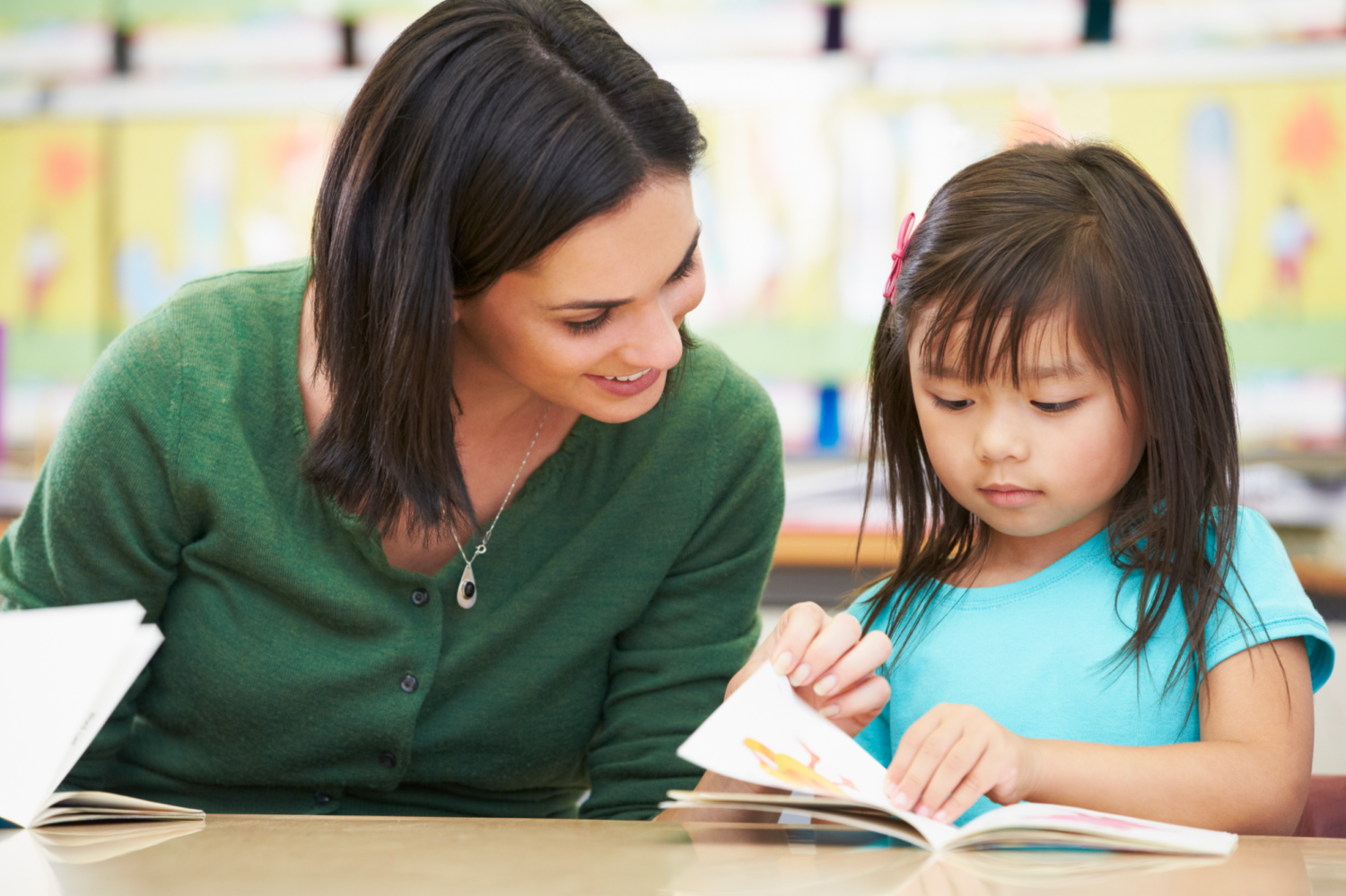 Image description: A volunteer reads with a young child in a classroom.